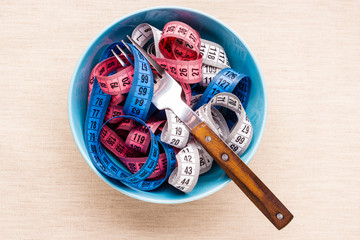 Many colorful measuring tapes in bowl on table