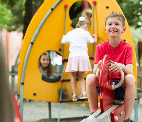 Fototapeta na wymiar Boy on swing at playground