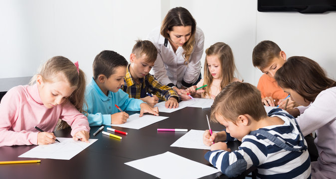 Little kids with teacher drawing in classroom