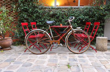 Red bike standing in front of garden table with chairs.