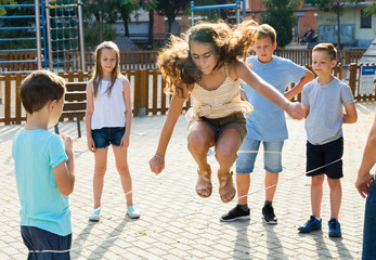 Happy children skipping on jumping elastic rope