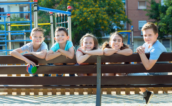 Five children sitting on a bench at the playground