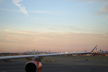 Airplane wing over New York city skyline.