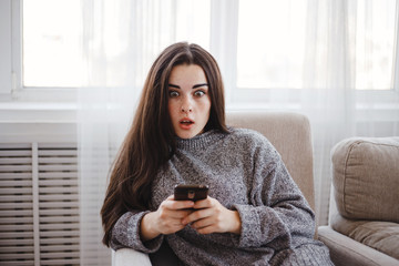 sale, shock, news, shopping, technology, electronic business. Excited shocked woman discovering offer at online store making purchases with mobile phone at home.