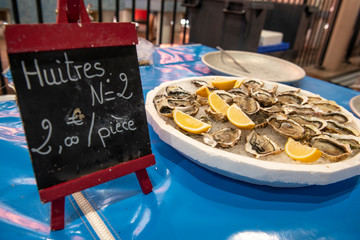 Preis steht auf kleiner aufgestellter Tafel auf französisch daneben eine Platte Austern mit Zitronen ausgestellt