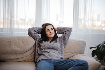 Young woman relaxing on a couch in living room. Home, comfort, dreaming and harmony