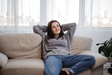 Young woman relaxing on a couch in living room. Home, comfort, dreaming and harmony