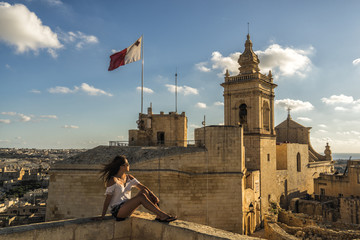 Woman sitting atop the medieval Gozo Citadel castle.   - obrazy, fototapety, plakaty