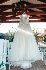 White wedding dress on hanger, hanging outside of home. Classic bridal clothing, meshy skirt and corset