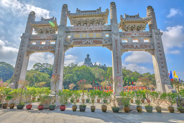 Obraz premium Malownicza brama w słoneczny dzień klasztoru Po Lin i Wielkiego Buddy na tle, ikona i symbol wyspy Lantau, popularnej miejscowości turystycznej w Hongkongu w Chinach.