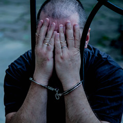 Upset handcuffed man imprisoned for crime, punished for serious villainy.