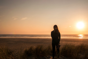 Fototapeta na wymiar Silhouette of a girl watching the sunset on the beach