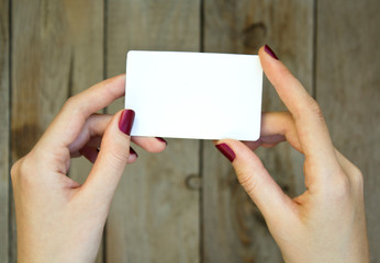 Woman hand holding blank card on wooden table.