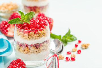 Pomegranate parfait - sweet organic layered dessert with granola flakes, yogurt and ripe fruit seeds.