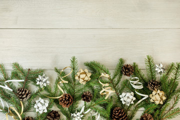 Spruce branches decorated with decorative ribbons and bows are laid out on a light background. Beautiful Christmas composition.