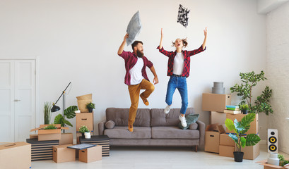 happy young married couple moves to new apartment and laughing,  jump, fight pillows.