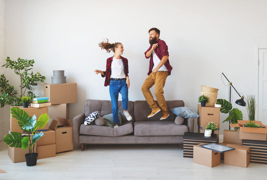 happy young married couple moves to new apartment and laughing,  jump, fight pillows.