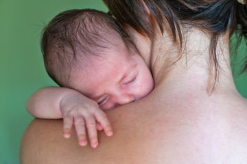 The newborn sleeps on his mother's shoulder