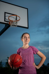 Girl holding a basketball at an outdoor court