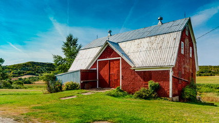 Red Barn in Blomidon - Blomidon, Annapolis Valley, Nova Scotia, Canada - September  25, 2018. Red barn in a field of green against a blue sky on a pleasant day in early autumn. © kenmo