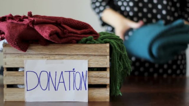 Woman folds clothes and puts inside a box for donation