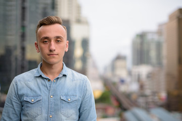 Young handsome man with blond hair against view of the city