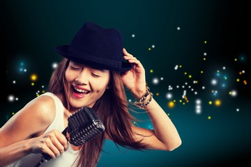 Young woman singing with microphone, wearing hat