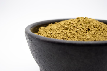 Maeng Da Kratom powder in black bowl isolated on a white background