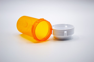 Empty orange medicine bottle with white cap on white background