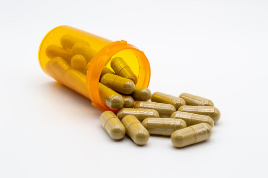 Yellow pill bottle with green pills spilling out