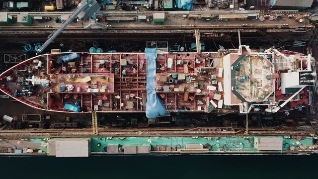 Drone flying above the cargo ship in the shipyard docks