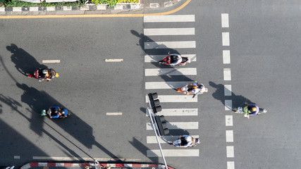 Fototapeta premium top aerial view of blur bikers ride the motorcycles to pass pedestrian crosswalk on road with the traffic pattern signage on the street
