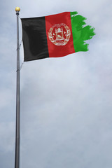 Worn and tattered Afghanistan flag blowing in the wind on a cloudy day