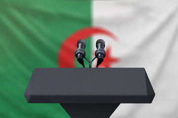 Podium lectern with two microphones and Algeria flag in background
