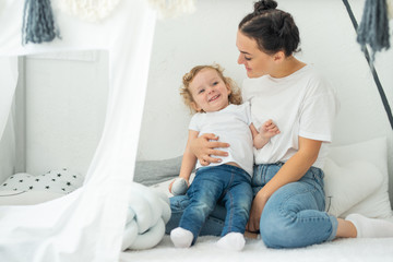 Happy mother plays with the child in a bright room, mother's day, happiness, love for her daughter, warm feelings