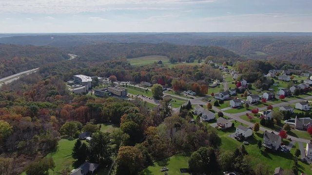 A forward high angle aerial view of the Pennsylvania landscape on an Autumn day. Fall foliage is visible on the horizon. Pittsburgh suburbs.  	