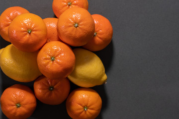 Mandarins and lemons on gray background