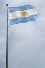 Worn and tattered Argentina flag blowing in the wind on a cloudy day