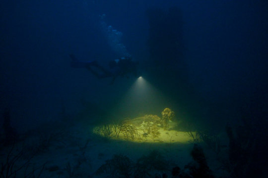 Lone night scuba diver on a wreck