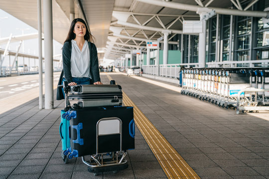 woman outside international airport with trolley