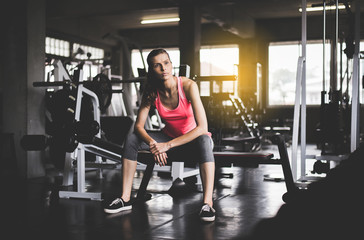 Fototapeta na wymiar Fit woman sitting and relax after the training session in gym,Concept healthy and lifestyle,Female taking a break after exercise and workout