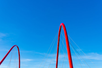 Partly beautiful red bending arch beam structure and cable of suspension bridge with background of...