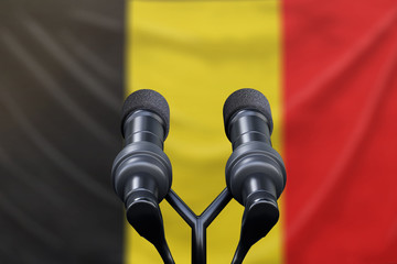 Podium lectern with two microphones and Belgium flag in background