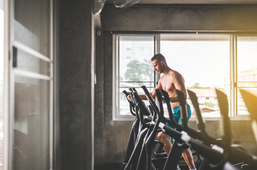 Naklejka premium Sport man doing exercises training on xtrainer machines,Cross fit body and muscular in the gym