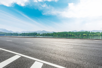 Fototapeta premium Asphalt road and beautiful mountain with lake under the blue sky