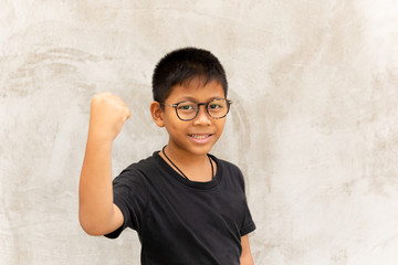 Obraz na płótnie Canvas Asian boy with glasses hands up and smiling over grey background.