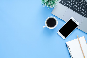 Office desk working space - Flat lay top view mockup photo of working space with laptop, smartphone, coffee up and notebook on blue pastel background. Pastel blue color background working desk concept