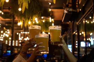 Friends toasting with glasses of beer at the pub brewery beautiful bokeh on Oktoberfest. Happy friend drinking, talking and clinking glasses at bar or pub.Leisure, friendship and communication concept