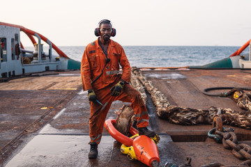 Seaman AB or Bosun on deck of offshore vessel or ship , wearing PPE personal protective equipment -...