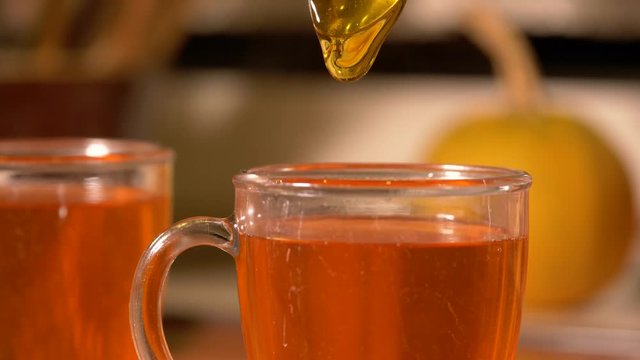 Adding a teaspoon of golden honey into a hot steamy teacup
